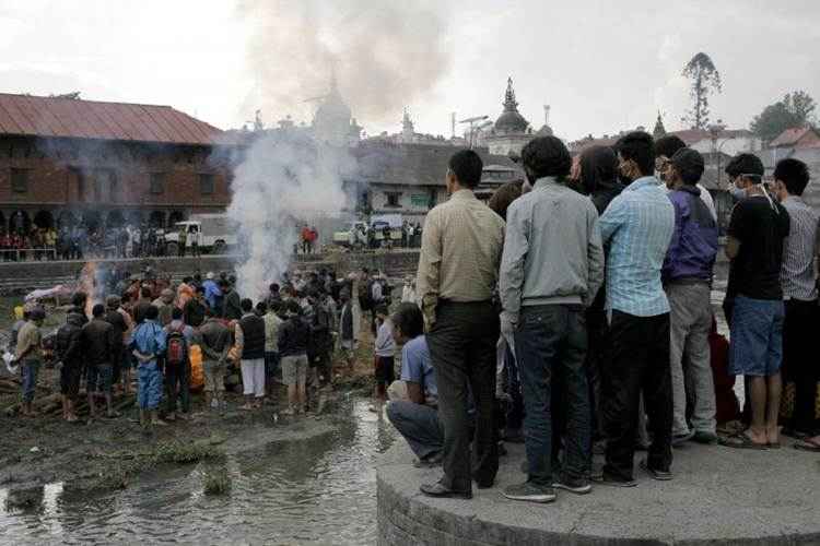 Nepaleses se reúnem diante de piras funerárias durante cremação em massa de vítimas do tremor, em Katmandu