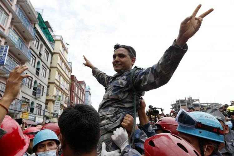 Um membro da polícia armada do Nepal celebra depois de ter puxado sobrevivente de 15 anos dos escombros de um edifício do hotel destruído em Katmandu