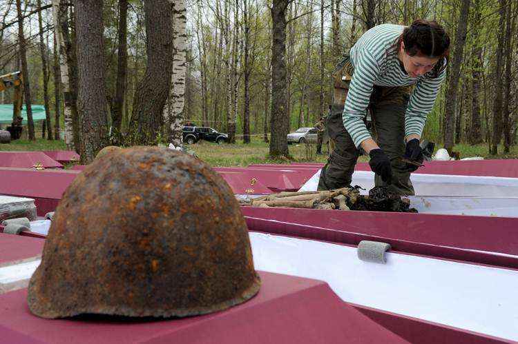 Um membro de grupo de pesquisa olha para restos mortais de soldados do Exército Vermelho mortos na Segunda Guerra Mundial , durante uma cerimônia de enterro fora São Petersburgo