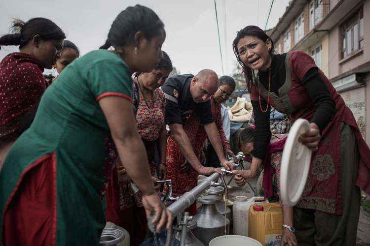 Ajuda humanitária distribui água fora da aldeia Bungamati na periferia de Katmandu