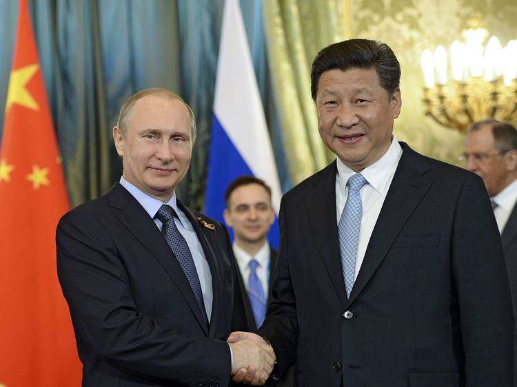 O presidente russo, Vladimir Putin  aperta a mão do presidente chinês, Xi Jinping , durante uma reunião no Kremlin em Moscovo