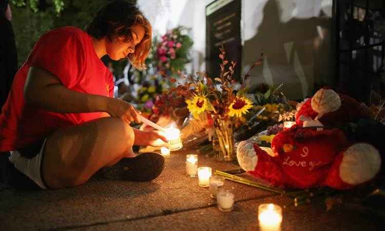 Mulher acende velas em homenagem às vítimas do massacre