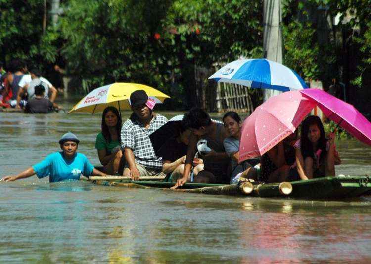 Moradores utilizam barcos de madeira e bambu para trafegarem ao longo de uma rua da vila inundada na cidade de Calasiao na província de Pangasinan, ao norte de Manila