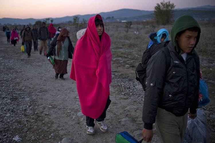 Migrantes e refugiados atravessam a fronteira greco-macedônia