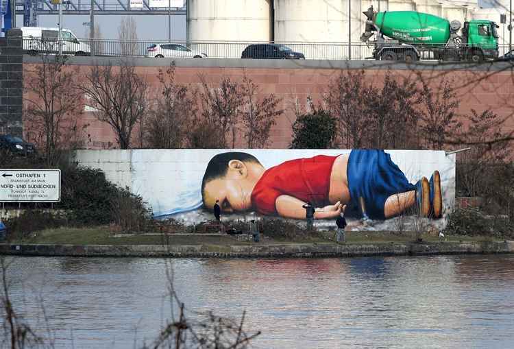 Artistas Justus Becker e Oguz Sen retrataram o jovem Alan Kurdi em um porto às margens do rio Meno, na cidade de Frankfurt, na Alemanha