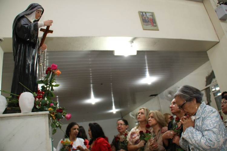 Católicos deixam rosas vermelhas aos pés da imagem: símbolo de devoção