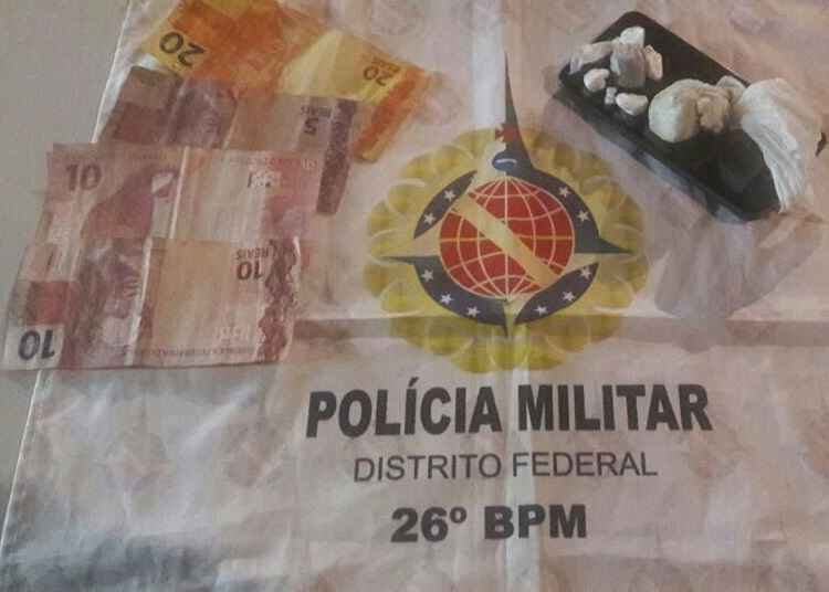 Dinheiro, drogas e um aparelho celular em cima da bandeira da Polícia Militar do Distrito Federal