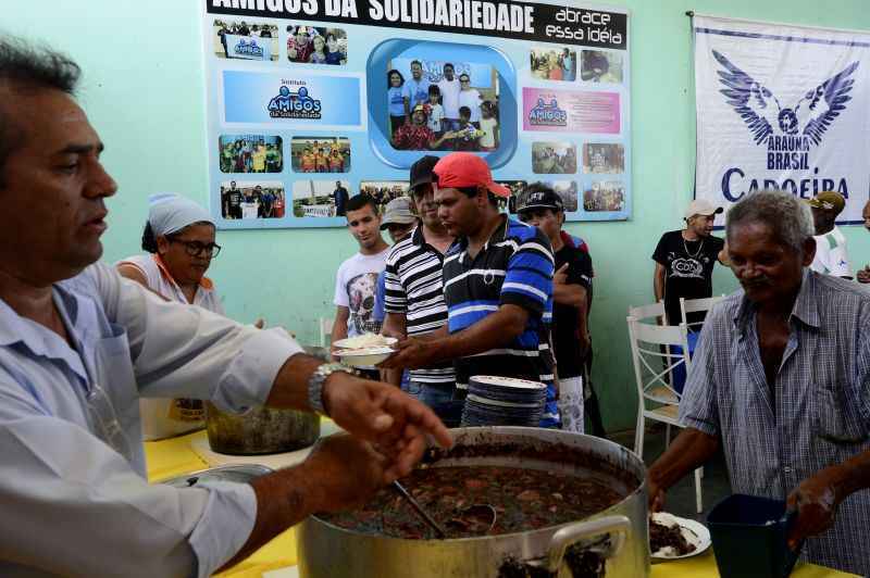 Em um galpão, voluntários servem a tradicional feijoada, às sextas-feiras: cerca de 600 pessoas beneficiadas, sem qualquer ajuda do Estado