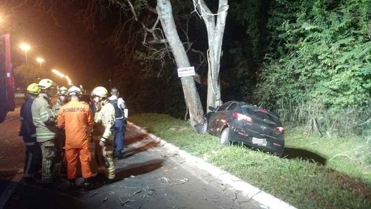 Carro HB20 batido em árvore e bombeiros ao lado fazendo socorro