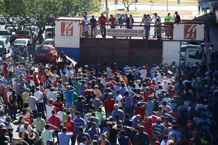 Várias pessoas reunidas ao redor de um carro de som