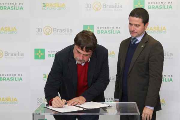 O presidente do Instituto de Arquitetos do Brasil (IAB-DF), Célio Melis Júnior, assina o contrato ao lado do chefe da Casa Civil em exercício, Fábio Pereira