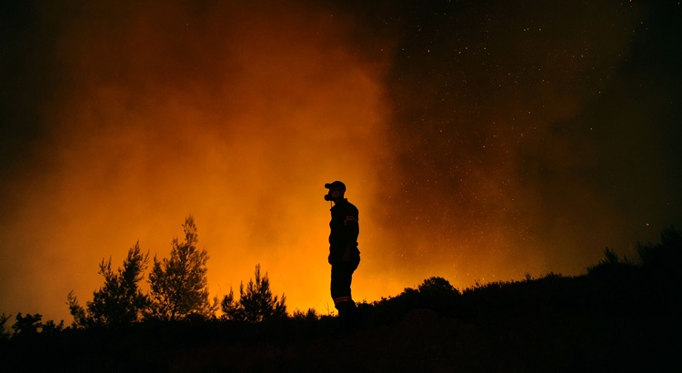 Um bombeiro tenta extinguir um incêndio perto da aldeia de Kapandriti, ao norte de Atenas, na Grécia