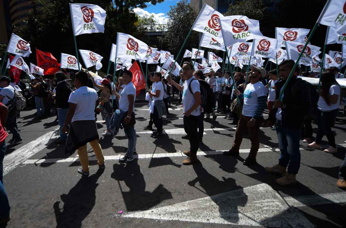 Manifestantes marcham com a bandeira do partido politico das Farc