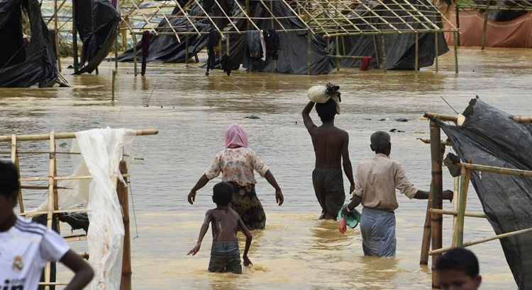 Os refugiados muçulmanos Rohingya atravessam a água submersa no campo de refugiados de Thyangkhali, no distrito bengali de Ukhia