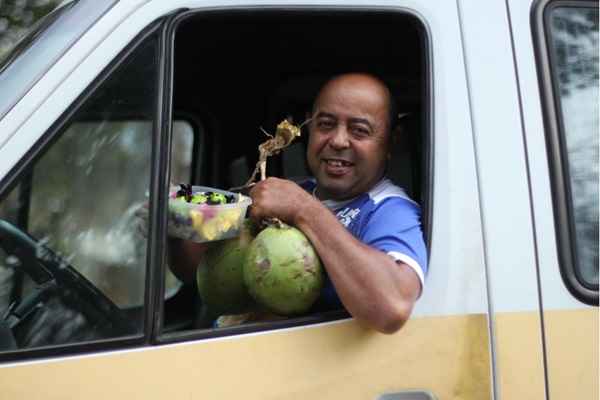 Entre uma atividade e outra, motorista de van escolar vende cocos numa barraca e comercializa bombons preparados pela esposa. Nos fins de semana, transporta grupos para eventos e excursões