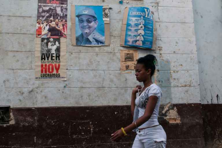 Mulher passa em frente â foto do presidente cubano, Raúl Castro, em Havana