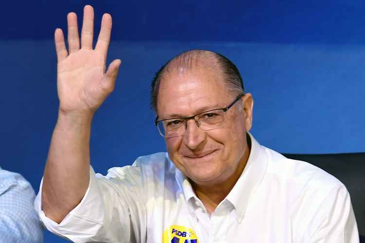 Geraldo Alckmin sentado acena para público