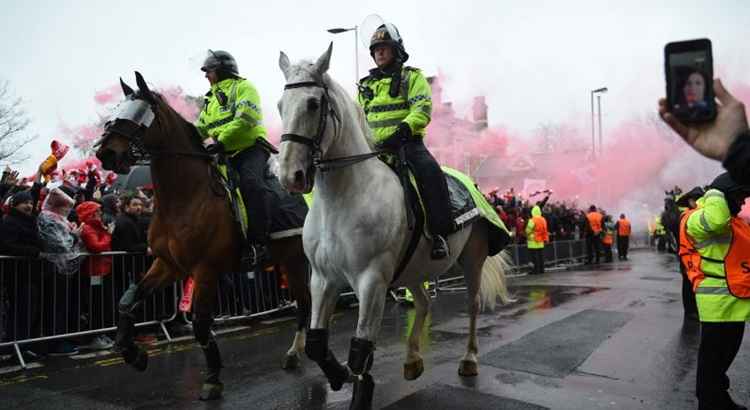 Polícia montada escolta um treinador que transporta a equipa do Liverpool para a primeira mão dos oitavos-de-final da UEFA Champions League entre Liverpool e Roma no estádio Anfield em Liverpool, no noroeste da Inglaterra