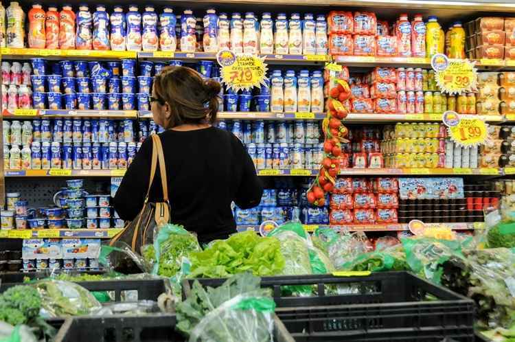 Mulher na frente das estantes de produtos do supermercado