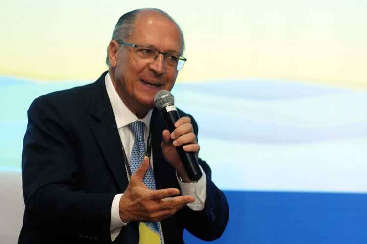 Geraldo Alckmin sentado com microfone na mão