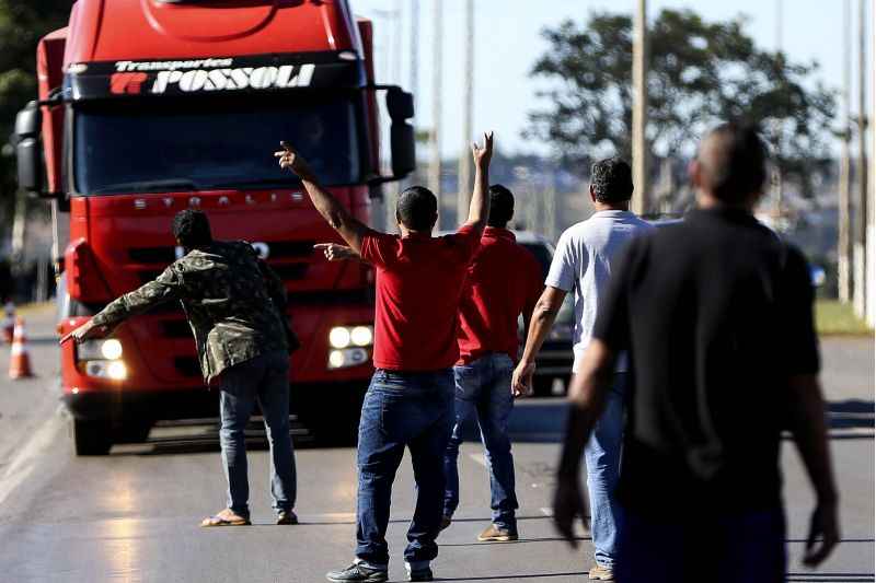 Caminhoneiros na rua gesticulando para outros caminhoneiros