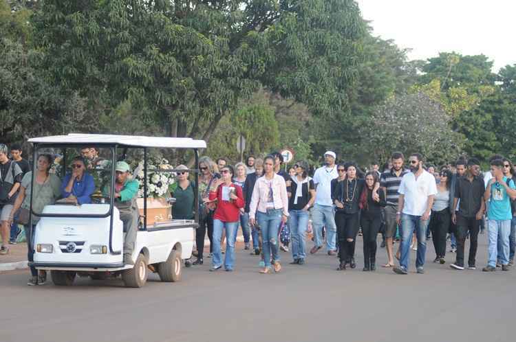 Carro de cemitério com pessoas seguindo atrás