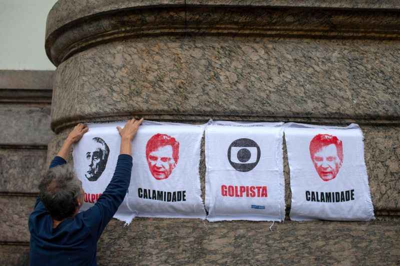 Um manifestante vende roupas de chão representando o presidente brasileiro Michel Temer, o prefeito do Rio de Janeiro, Marcelo Crivella, e o logo da Globo, fora da Câmara Municipal do Rio de Janeiro