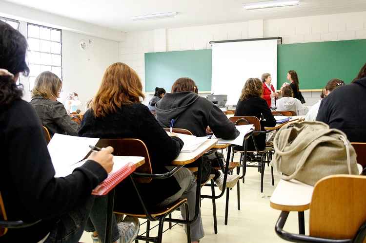 Uma sala de aula com estudantes virados de frente para o quadro