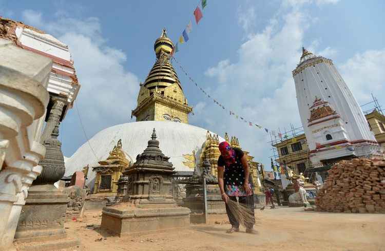 Mulher varrendo área em frente ao templo