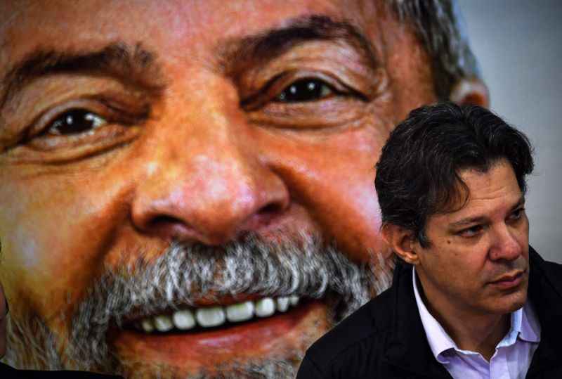 Haddad com foto de Lula ao fundo