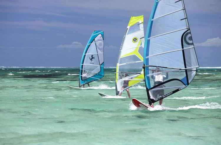 Trio pratica vela sobre o mar