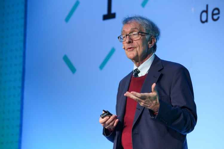 Howard Gardner palestra vestido em um terno. Ele usa óculos e gesticula com as mãos