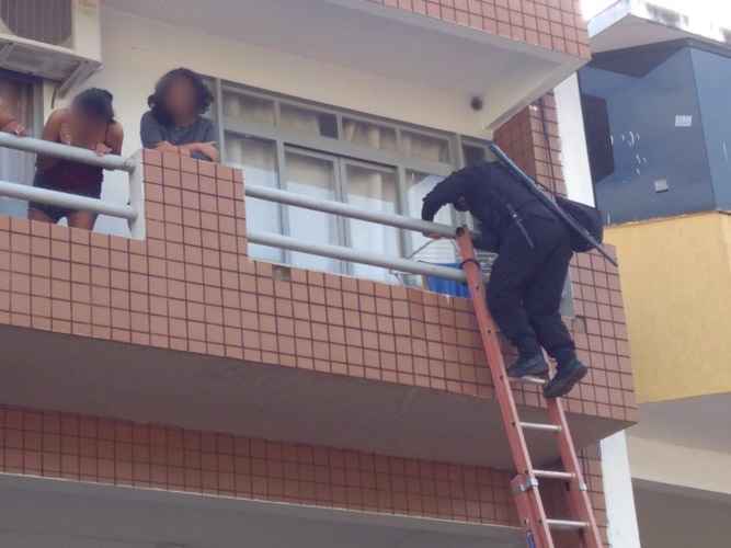 Momento em que um bombeiro militar sobe à varanda e resgata as vítimas