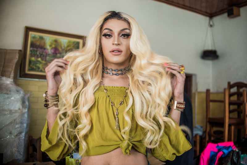 Pabllo Vittar com longos cabelos loiros e ondulados, usando uma blusa amarela