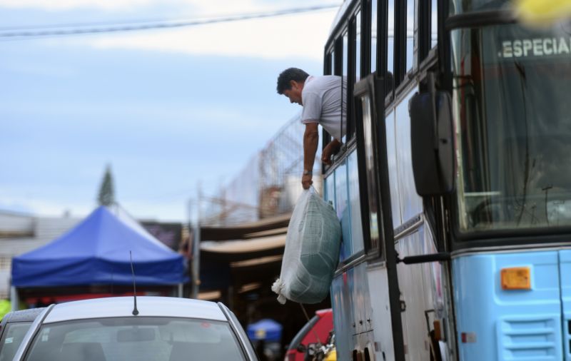 Ambulante descarrega mercadoria pela janela de um ônibus vindo de Goiânia, com outros vendedores