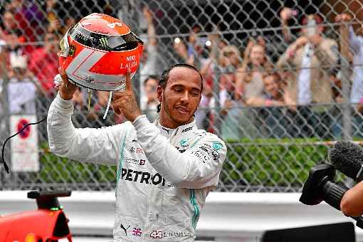 Hamilton ergue o capacete de Lauda durante a comemoração pela vitória: britânico segue dominante rumo ao hexacampeonato