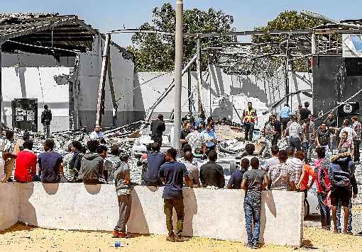 Migrantes observam o impacto do bombardeio no centro de detenção