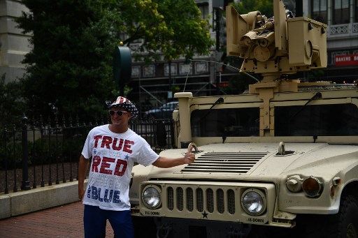 Foliões do Dia da Independência posam em frente a um Humvee estacionado em uma rua em Washington, DC.