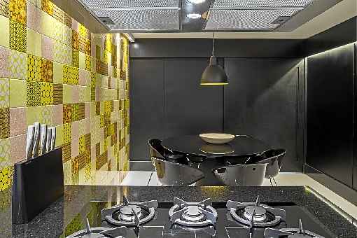 Eduardo Sáinz e Lilian Glayna assinam o projeto do espaço gourmet com jogo de cadeiras em acrílico. O preto das peças proporciona uniformidade ao ambiente, que tem o tom explorado em diversos elementos. O amarelo traz cor ao local, deixando-o mais moderno.