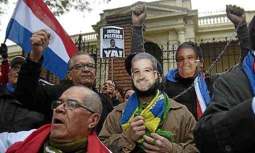 Ativistas com as bandeiras do Paraguai e do Brasil, e com máscaras de Mario Abdo Benítez, protestam contra o presidente: suspeita de traição à Pátria