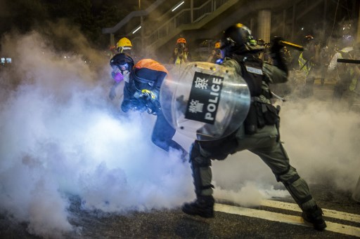 Vestidos de preto e com o rosto protegido por máscaras, muitos manifestantes pediam que se salvasse Hong Kong da tirania, diante de uma delegacia protegida por agentes com equipamento antichoque.