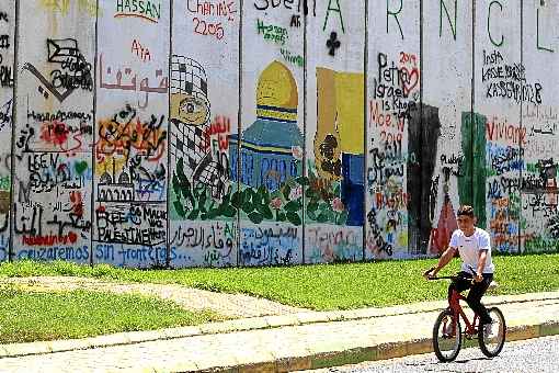 Garoto libanês passa de bicicleta ao longo da fronteira com Israel, perto do vilarejo de Kfar Kila, no sul do Líbano: soberania e independência exaltadas