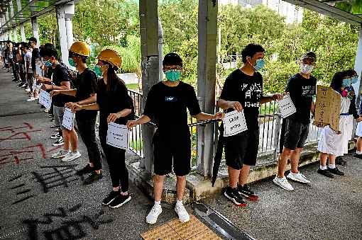 Universitários e colegiais participam de uma cadeia humana no distrito de Tuen Mun: desafio incessante