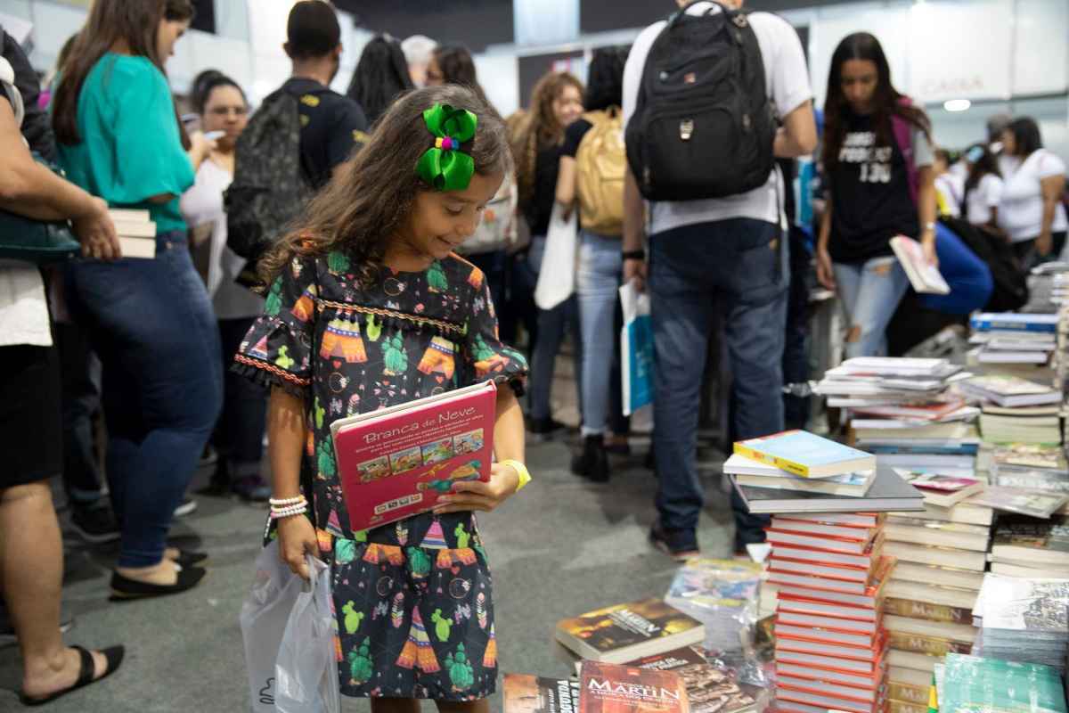 menina olha para livros na bienal do livro