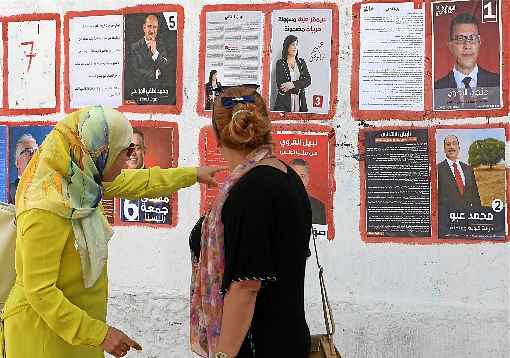 Mulheres tunisianas observam cartazes com fotos dos presidenciáveis, na capital: eleições históricas