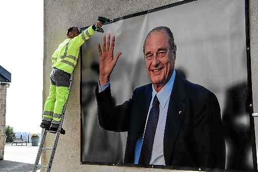 Trabalhador instala outdoor com foto de Jacques Chirac em frente ao museu com o nome do ex-presidente em Sarran, na França: longevidade política