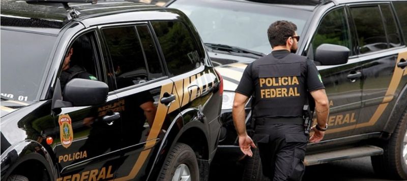 Agentes da Polícia Federal próximos a viaturas da PF