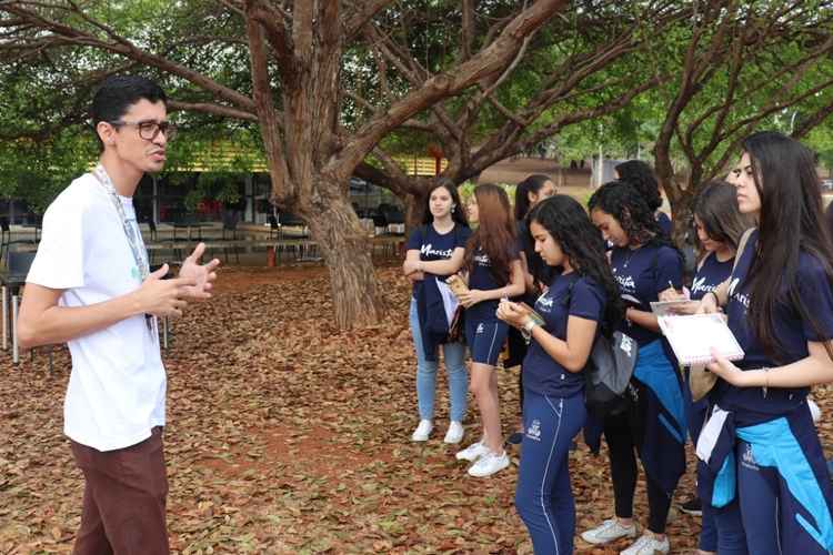 Professor de biologia Rodrigo Xavier dá aula sobre vegetação do cerrado, mostrando o objeto de estudo para o alunos