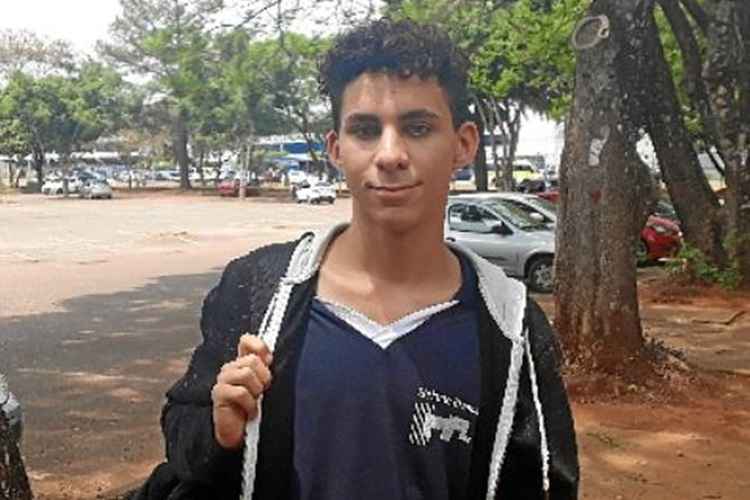 Jovem de cabelo enrolado e camiseta preta, onde se vê a logo do Elefante Branco