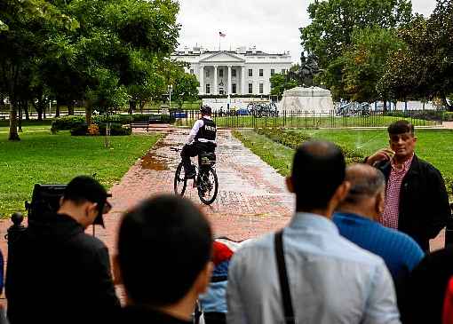 Turistas diante da Casa Branca, vigiada por agente do Serviço Secreto em bicicleta: investigação de impeachment deixa Washington em suspense